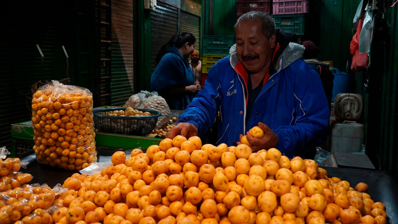 Comerciante en plaza de mercado vendiendo papa criolla